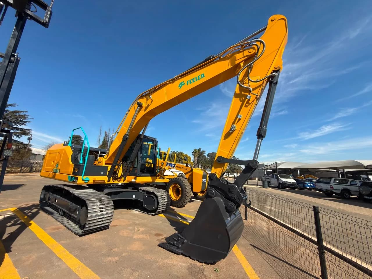 A yellow Feeler tracked excavator with the bucket extended.