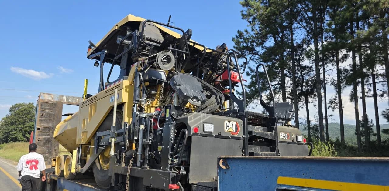 A Caterpillar asphalt paver strapped down on a lowbed trailer.