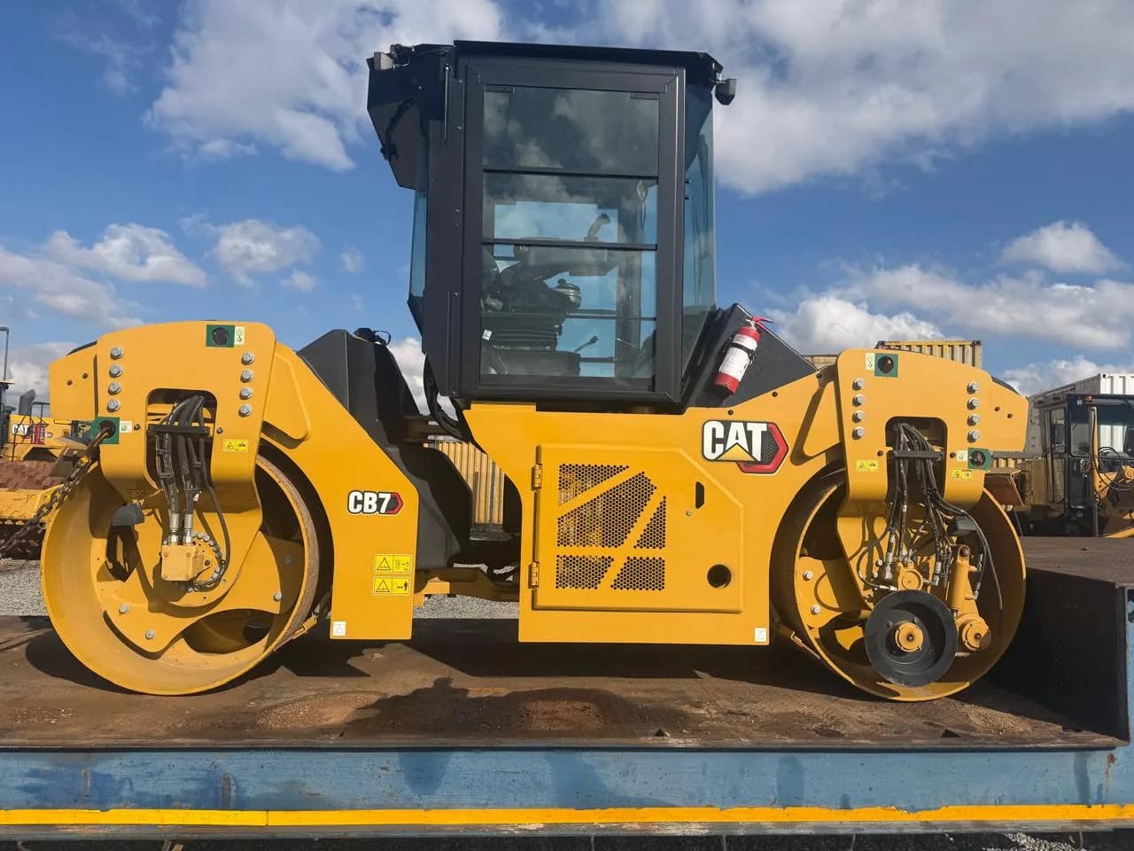 A CAT CB7 tandem roller on a truck bed.