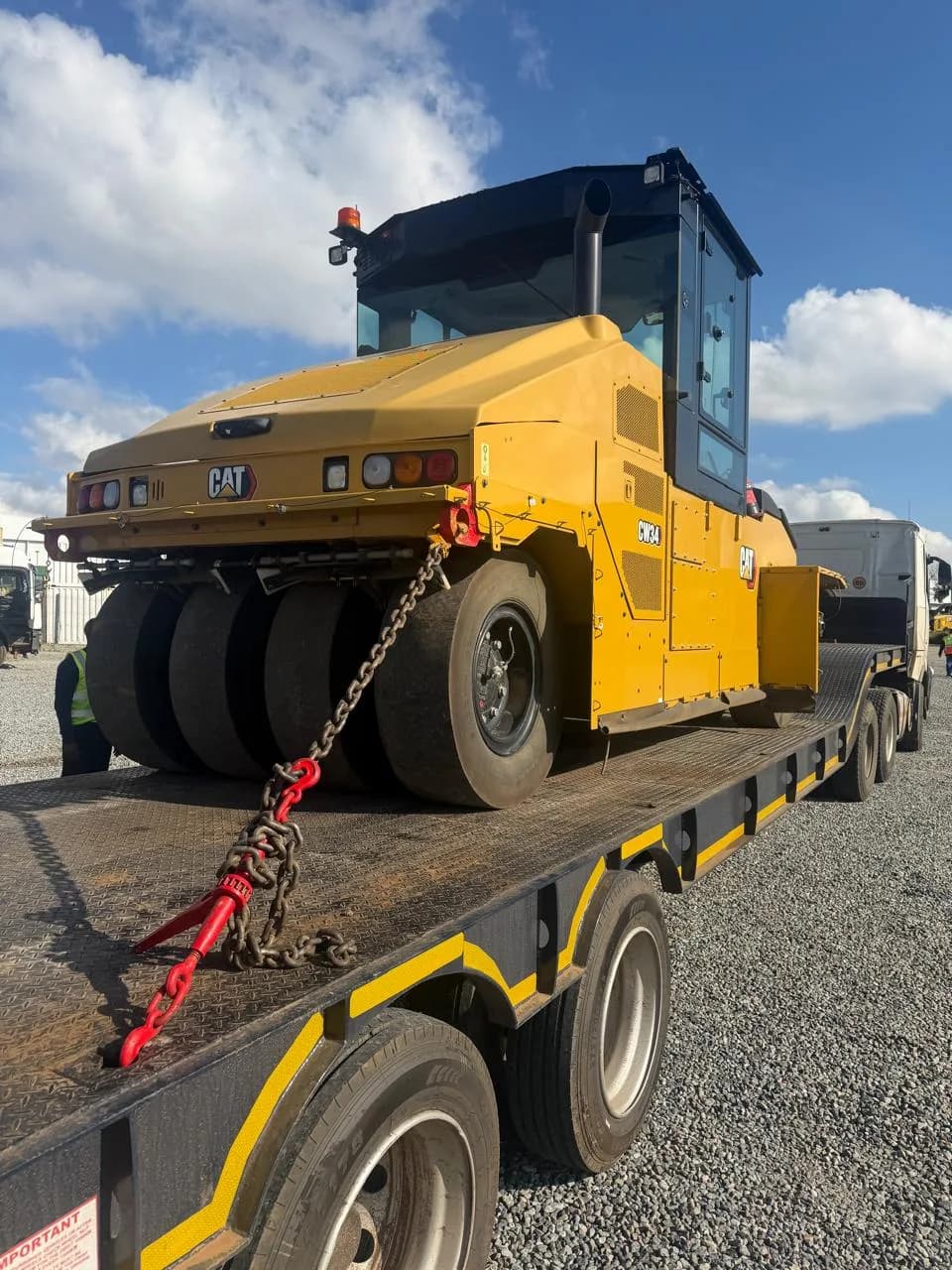 A CAT CW34 pneumatic-tyre roller loaded on a lowbed trailer.